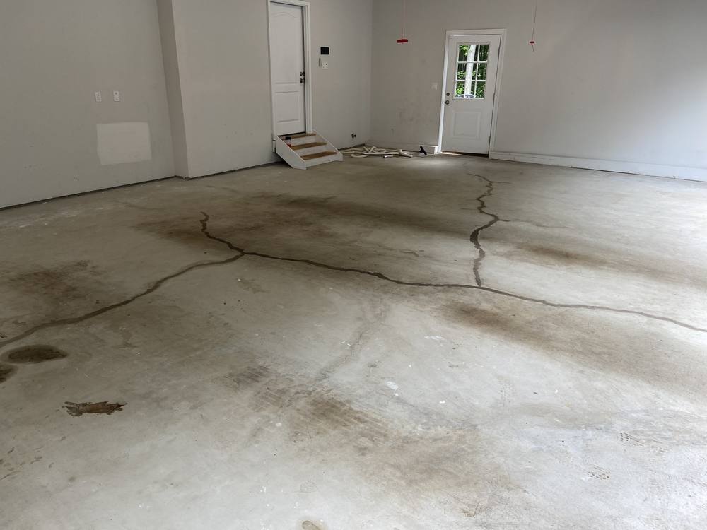 Garage floor before coating, bare concrete with visible cracks